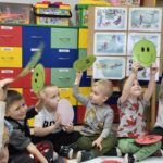 Dzieci za pomocą zelonych i czerwonych buziek odpowiadają na pytania policjantów