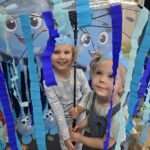 Dziewczynki-ukrywaja-sie-przed-deszczem-pod-parasolem