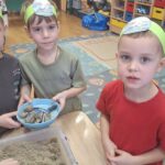 Przedszkolaki ze śmieciami wyciagniętymi z piasku