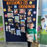 Chłopiec pozuje przy tablicy z konkursowymi pracami