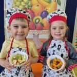Dzieci prezentują swoją salatkę owocową