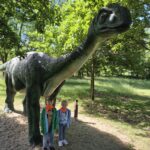 Dzieci stoją przy posągu dinozaura