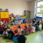 Pięciolatki siedzą na dywanie z sześciolatkami