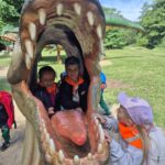 Przedszkolaki zaglądają do paszczy dinozura