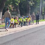 Dzieci idą chodnikiem z Policjantem w stronę pasów