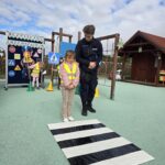 Dziewczynka przechodzi przez atrapę pasów dla pieszych z policjantem