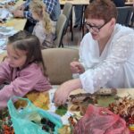 dzieci wraz z seniorami wykonują jesienne ludziki