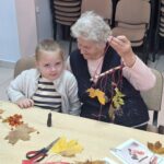 dzieci wraz z seniorami wykonują jesienne ludziki
