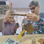 dzieci wraz z seniorami wykonują jesienne ludziki