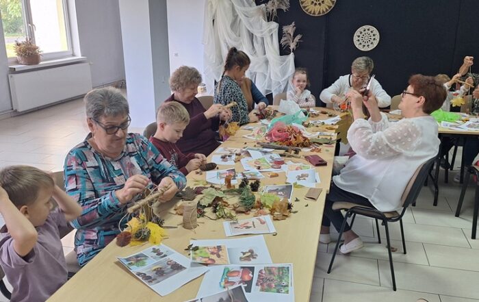 dzieci wraz z seniorami wykonują jesienne ludziki