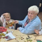 dzieci wraz z seniorami wykonują jesienne ludziki
