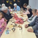 dzieci wraz z seniorami wykonują jesienne ludziki