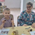 dzieci wraz z seniorami wykonują jesienne ludziki