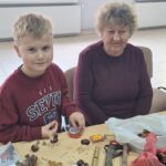 dzieci wraz z seniorami wykonują jesienne ludziki