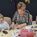 dzieci wraz z seniorami wykonują jesienne ludziki