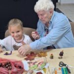 dzieci wraz z seniorami wykonują jesienne ludziki