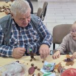 dzieci wraz z seniorami wykonują jesienne ludziki