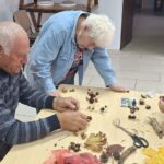 dzieci wraz z seniorami wykonują jesienne ludziki
