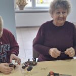 dzieci wraz z seniorami wykonują jesienne ludziki