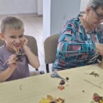 dzieci wraz z seniorami wykonują jesienne ludziki