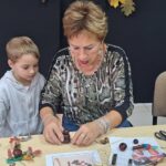 dzieci wraz z seniorami wykonują jesienne ludziki