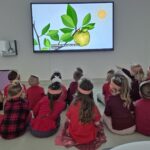 Przedszkolaki oglądają film edukacyjny o jabłku